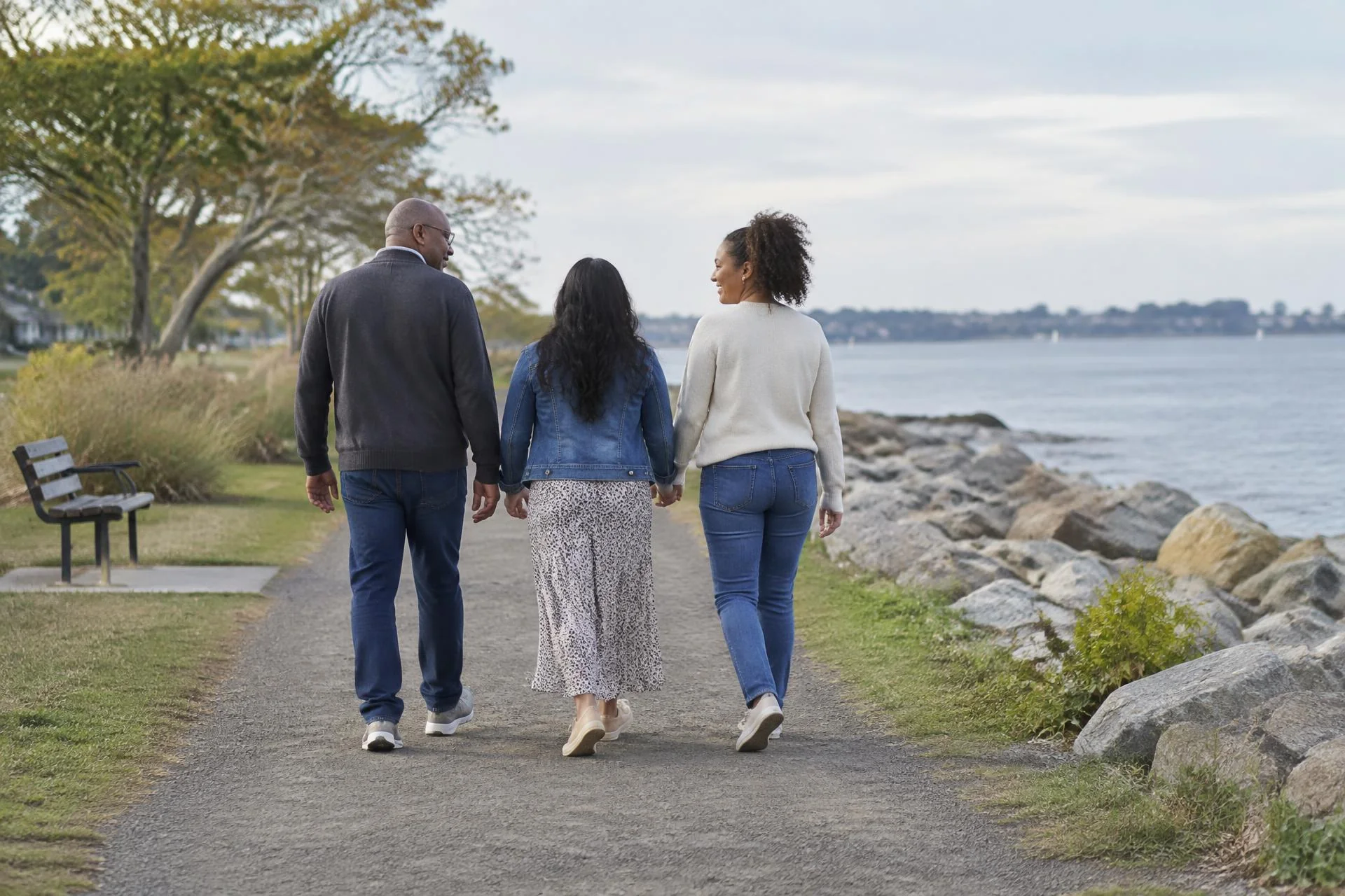Three adult family members walking together along a Long Island waterfront.